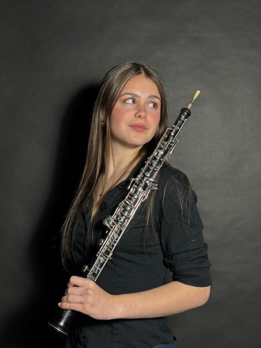 Emily Carrington seated beside a window holding her oboe